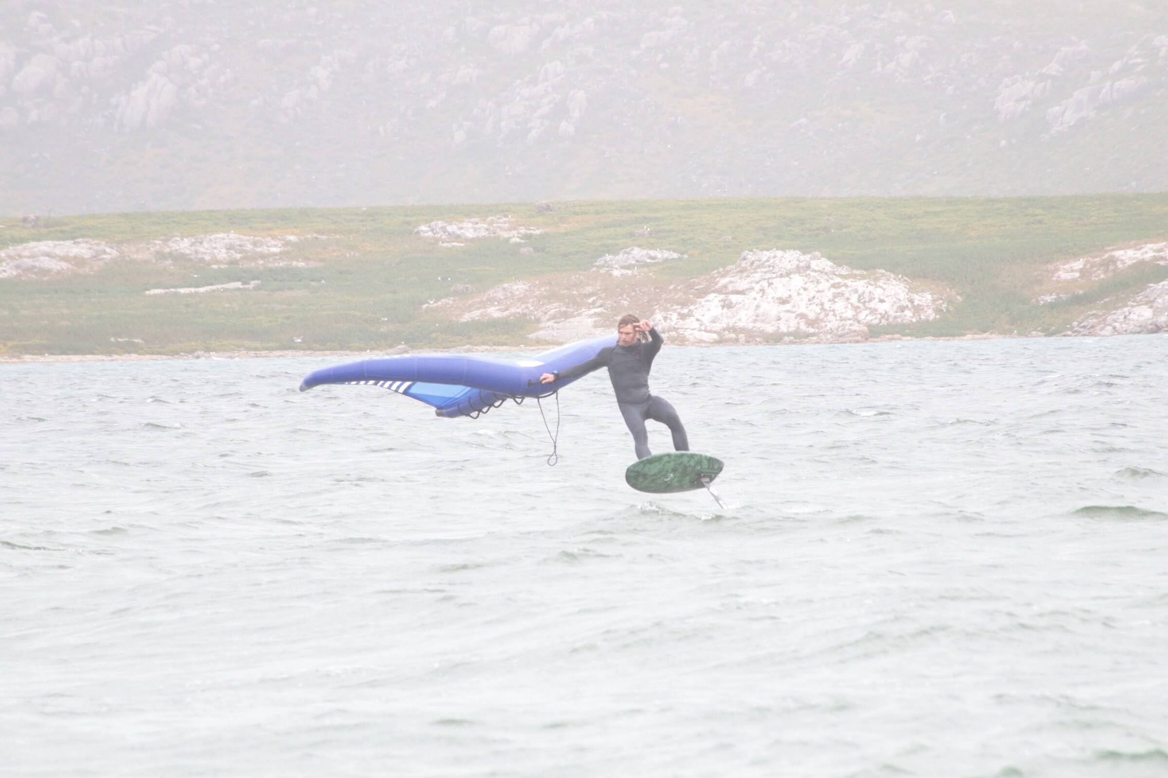 Kitesurf foiling action over turquoise water.