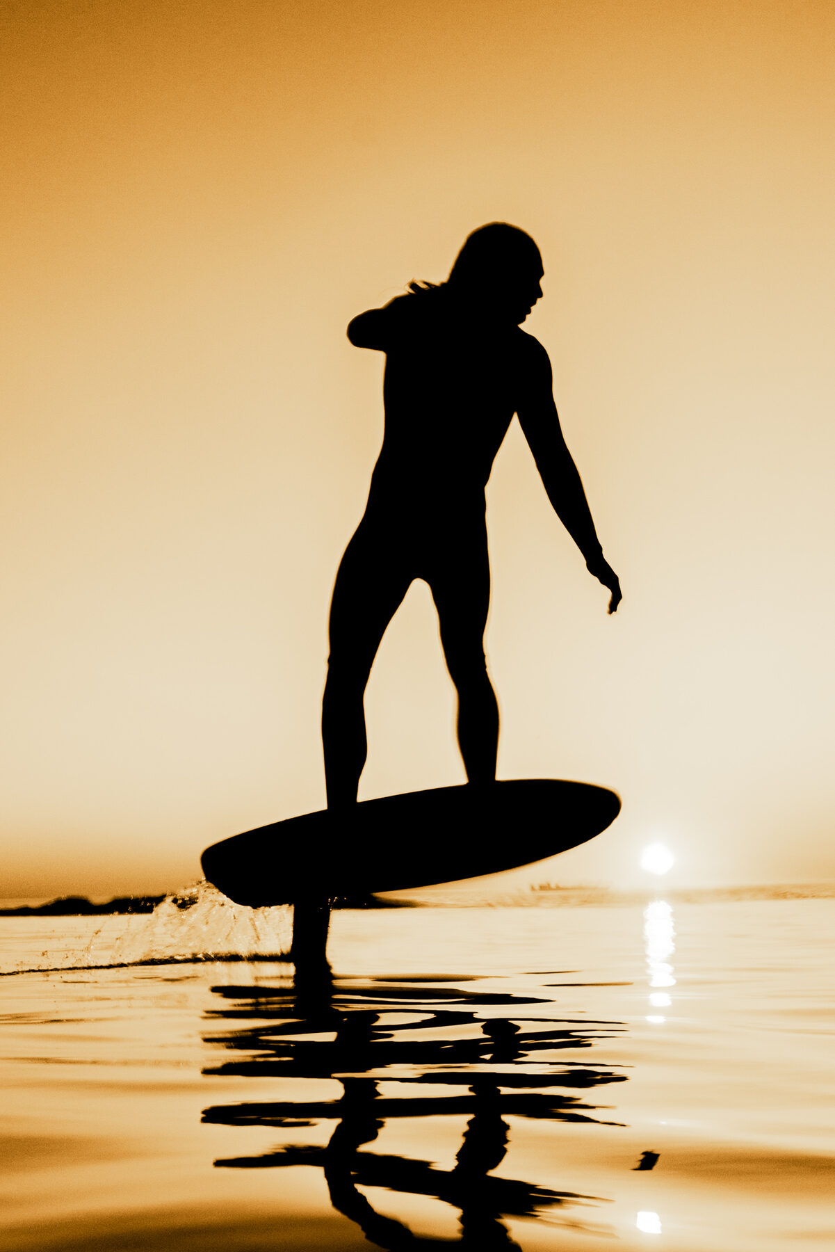 Low-light water session with warm reflections across swell.